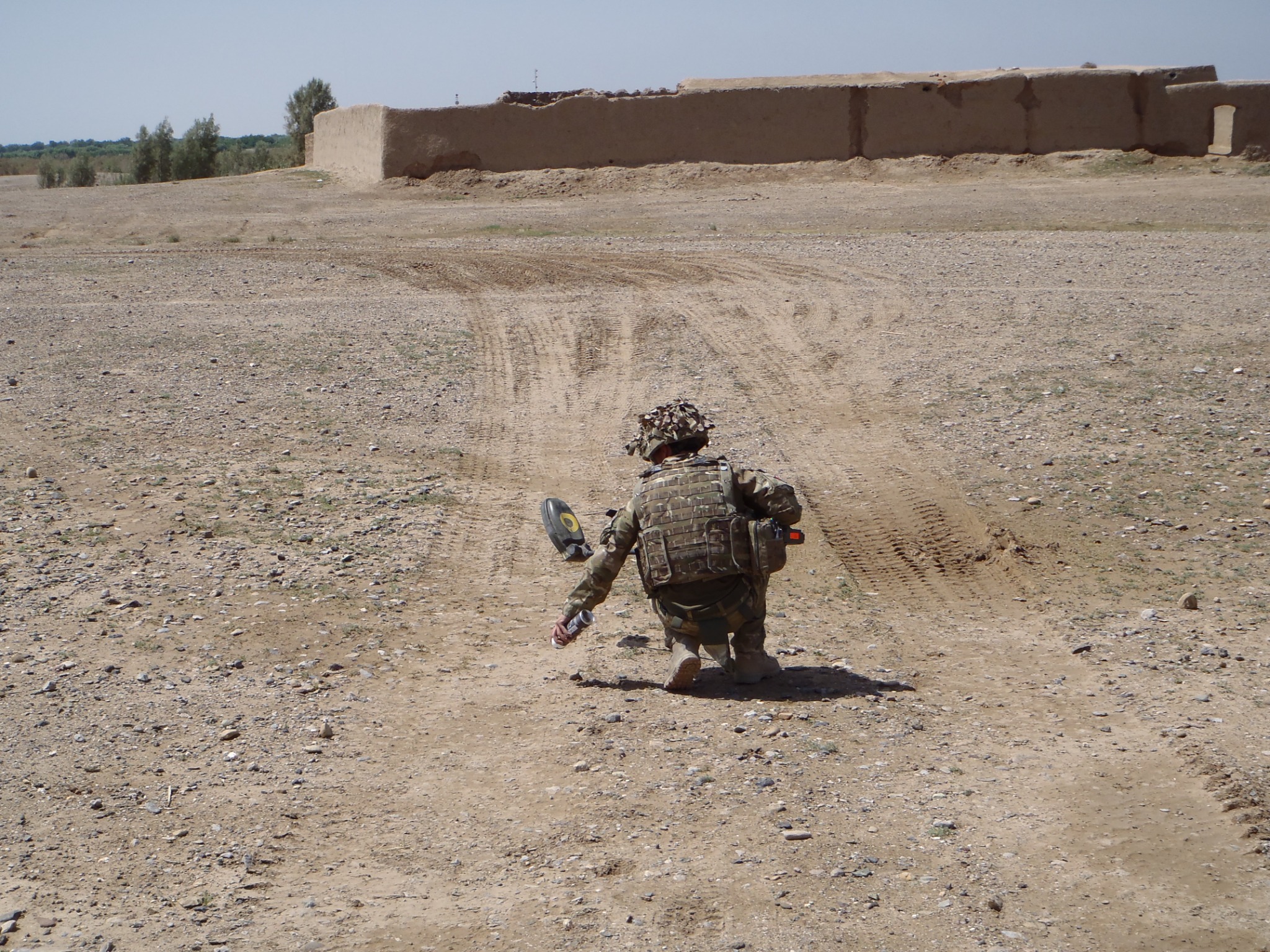 A soldier kneeling in the field, focused on the task at hand